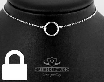 Puede incluir: Un collar de cadena de plata con un simple colgante circular. El collar está en un expositor negro.