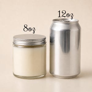 May include: A clear glass candle jar with a silver metal lid labeled 8oz, positioned next to a silver aluminum beverage can labeled 12oz. The candle jar contains a solid off-white wax, and both items are displayed side by side for size comparison.