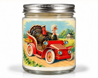 May include: A clear glass candle jar with a silver metal lid featuring a label illustration of two turkeys in a red vintage automobile. One turkey wears a small white cap, and the other wears a white bonnet. The background shows a rural landscape.