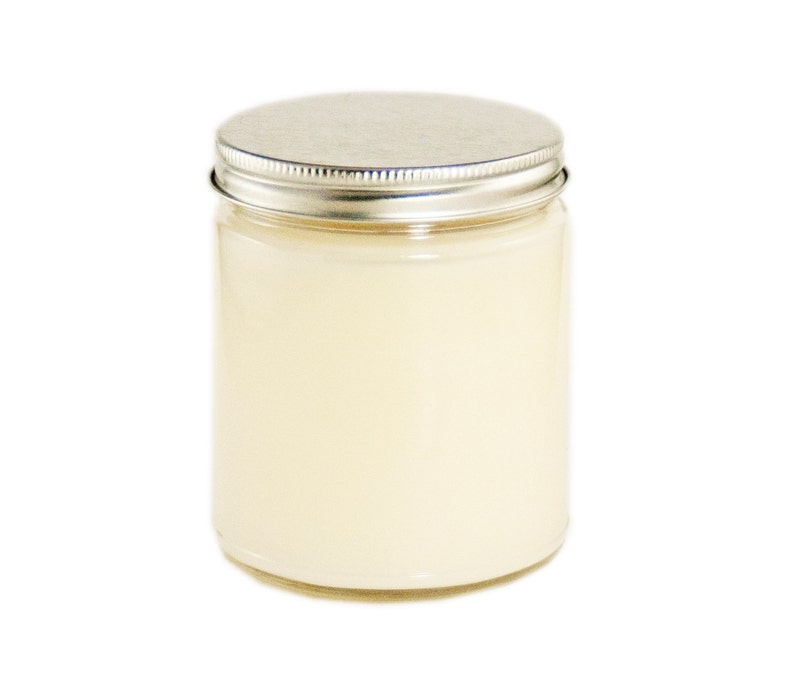 May include: A clear glass jar with a silver lid filled with a white candle.