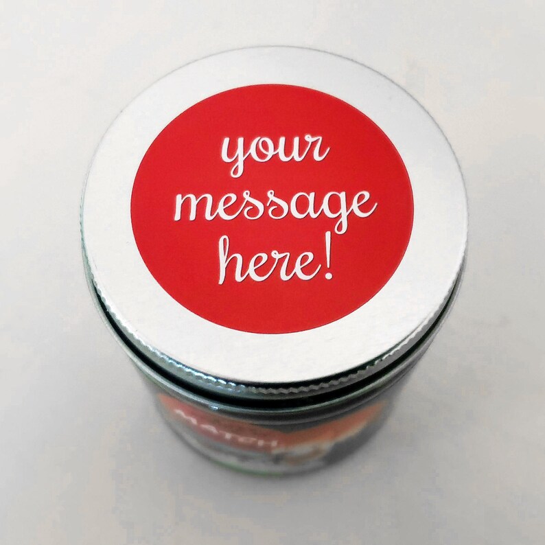 May include: A silver lid with a red circle sticker that says "your message here!" on top of a glass jar.