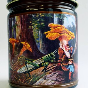 May include: A brown glass jar candle with a colorful label depicting a whimsical scene of a gnome sitting under a mushroom with a grasshopper in the foreground. The label features a forest background with trees and other mushrooms.