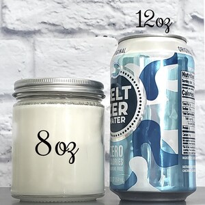 Side-by-side comparison of an 8 oz glass jar soy candle next to a standard 12 oz soda can, illustrating the candle’s size for scale
