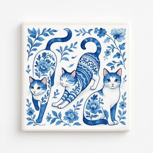 May include: Square ceramic tile featuring three blue and white cats in various poses, surrounded by floral and leaf designs. The cats have intricate patterns and are set against a white background, creating a decorative and artistic piece.