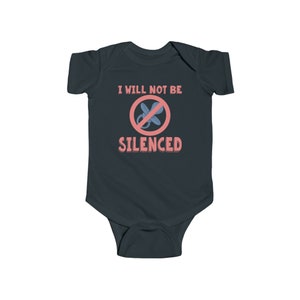 May include: A dark blue baby onesie with the text "I will not be silenced" in pink and a red circle with a diagonal line through a blue pacifier.