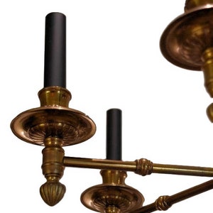 May include: A brass chandelier with black candle holders. The chandelier has a traditional design with ornate details.