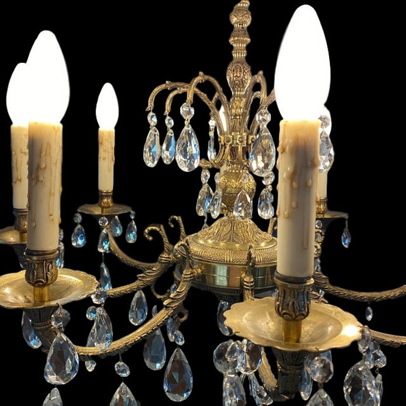 May include: A gold-toned chandelier with crystal drops and six candle-style light bulbs. The chandelier has a traditional design with ornate details.
