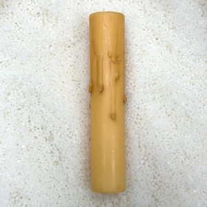 May include: A single, tall, ivory-colored candle with a drip design. The candle is sitting on a white surface.