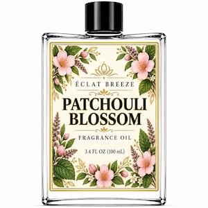 Puede incluir: Un frasco de vidrio rectangular de aceite aromático Eclat Breeze Patchouli Blossom con tapa negra. La etiqueta tiene un fondo crema, borde dorado e ilustraciones de flores rosas y hojas verdes, con el texto 100 mL impreso en la parte inferior.