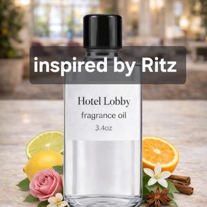 May include: A clear glass bottle with a black cap labelled "Hotel Lobby fragrance oil 100ml" and the text "inspired by Ritz". The bottle is surrounded by lemon, orange, rose, and spices.