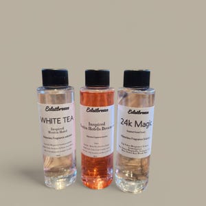 May include: Three clear glass bottles with black caps and white labels. The labels have the text "Eclatbreeze" and the names of the scents: "White Tea", "Inspired Westin Hotels Dream", and "24k Magic".