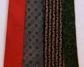 May include: Four neckties in a row, each with a unique pattern and color. The first is a solid red with a textured weave. The second is gray with small white floral designs. The third is black and brown with a zig-zag pattern. The last is dark green with a paisley design.
