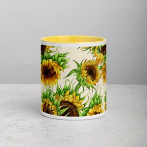 Puede incluir: Taza de cer&aacute;mica blanca con borde amarillo y un patr&oacute;n de girasoles sobre un fondo crema.