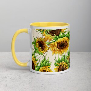 Puede incluir: Taza de cer&aacute;mica blanca con borde amarillo y un patr&oacute;n de girasoles sobre un fondo crema.