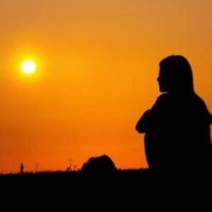 May include: Silhouette of a person sitting with their arms crossed, looking out at a bright orange sunset.