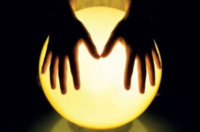 May include: A glowing crystal ball with two hands resting on top of it.