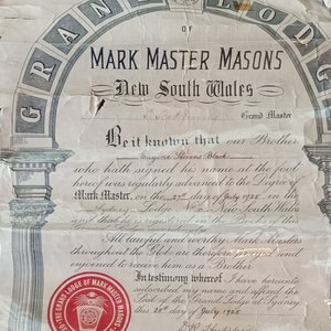Puede incluir: Un documento antiguo de la Gran Logia de Maestros Masones de Marca de Nueva Gales del Sur, Australia, dentro de pl&aacute;stico. El documento presenta texto e ilustraciones ornamentadas, incluyendo un dise&ntilde;o de suelo a cuadros y un sello rojo.