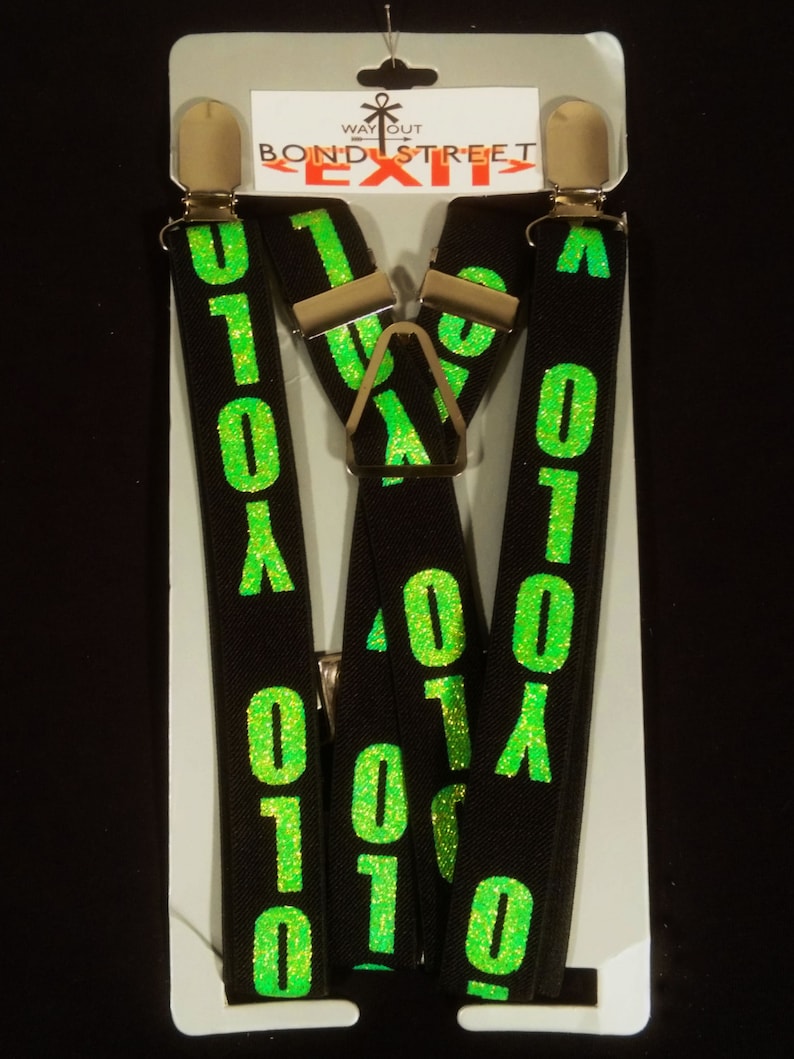 May include: Black suspenders featuring a bright green glittery "0101" pattern. The suspenders have silver-coloured metal clips and a Y-back design. The product is displayed on a white cardboard backing with the text "WAY OUT BOND STREET EXIT".