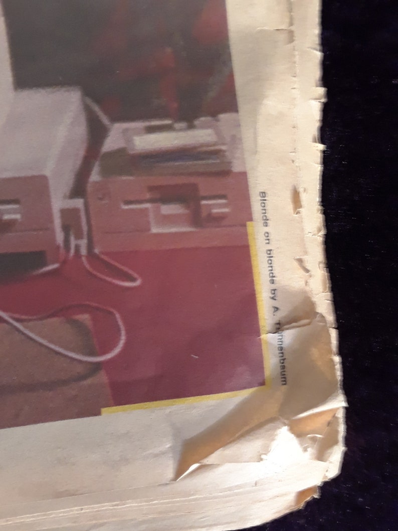 May include: A torn page with the text "Blonde on blonde by A. Tannenbaum" is visible. The image shows a red floor and a white table with a red chair.