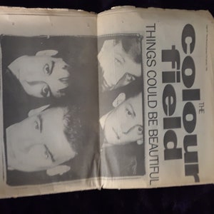May include: An open newspaper page featuring a black and white image of a band. The text reads "The Colour Field" and "Things Could Be Beautiful". Additional text states "7 & 12 inch recordings".