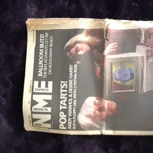 May include: A vintage magazine spread featuring Andy Warhol and Debbie Harry. Headlines include "Pop Tarts!" and "Blondes Have More Fun!" The image also shows a computer with a screen displaying a pop art image.