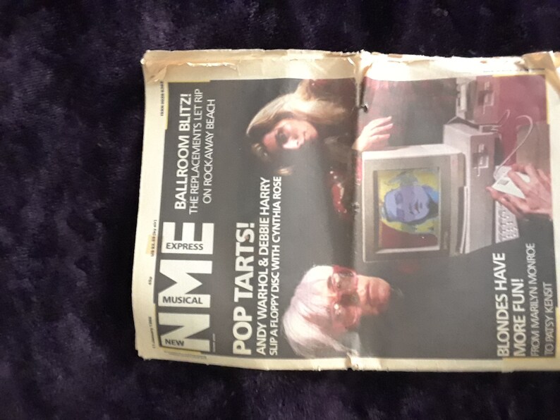 May include: A vintage magazine spread featuring Andy Warhol and Debbie Harry. Headlines include "Pop Tarts!" and "Blondes Have More Fun!" The image also shows a computer with a screen displaying a pop art image.