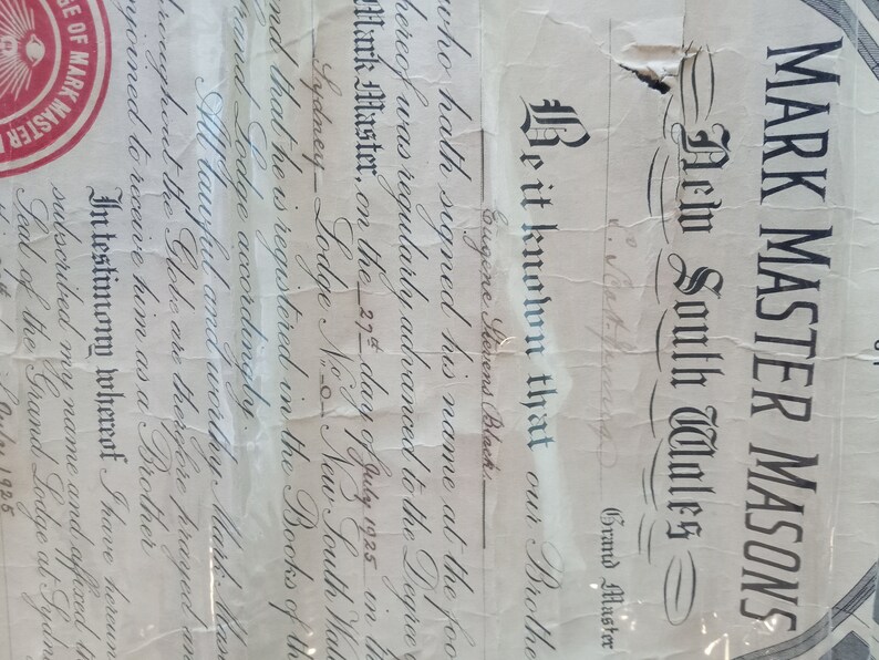 Puede incluir: Un documento antiguo de los Mark Master Masons de Nueva Gales del Sur, Australia, con caligraf&iacute;a ornamentada y un sello rojo. El texto incluye el nombre de Eugene Stevens Black y la fecha del 27 de julio de 1925.