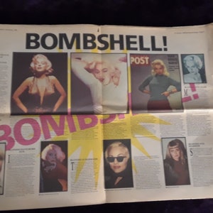 May include: A newspaper spread with the headline "BOMBSHELL!" in large black letters. The pages feature images of blonde women, including Marilyn Monroe, and the word "BOMB" in pink. The newspaper is on a dark purple surface.