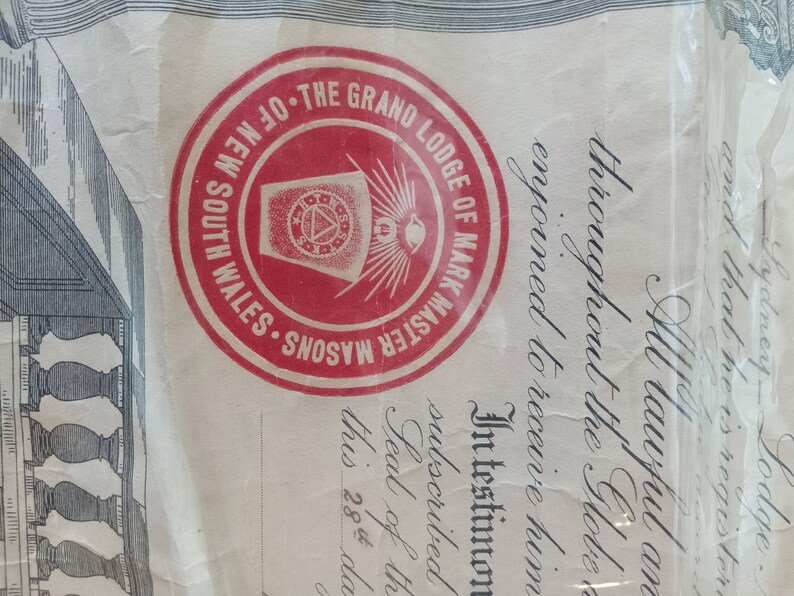 Puede incluir: Documento con un sello circular rojo con la inscripci&oacute;n "THE GRAND LODGE OF MARK MASTER MASONS OF NEW SOUTH WALES". El sello rodea un emblema central con un dise&ntilde;o de tri&aacute;ngulo y ojo. El documento tiene texto manuscrito.