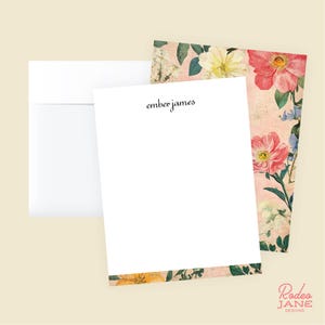 May include: A stationery set featuring a white envelope, a blank white notecard with the text "ember james", and a floral patterned card. The floral pattern includes pink, yellow, and blue flowers on a light pink background. The Rodeo Jane Designs logo is in the bottom right corner.