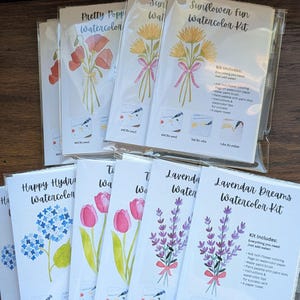 May include: A collection of watercolor kits in clear plastic sleeves, each featuring a 4x6 inch flower coloring page, a water paint brush, a paint palette with paint dots, instructions, and a paper towel. Designs include poppies, sunflowers, hydrangeas, tulips, and lavender.