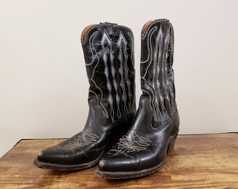 May include: A pair of black leather cowboy boots with white stitching. The boots have a pointed toe and a high heel.