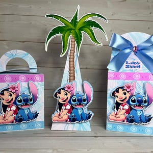 Op de afbeelding: Drie decoratieve dozen met de personages Lilo en Stitch. De dozen zijn blauw, roze en wit met een palmboom uitsparing. E&eacute;n doos heeft een handvat, een andere is kegelvormig en de derde heeft een blauw lint met de tekst "Lilo & Stitch".