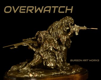 May include: A bronze sculpture of two soldiers in camouflage gear, one holding a rifle and the other a sniper rifle. The sculpture is titled "Overwatch" and is signed "Burgo Art Works".