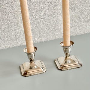 A pair of Silver candle stick holders on a square foot .  Candlestick Pair.   7 cm height. SET of 2 Pieces.