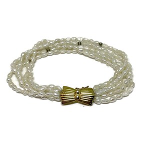 Fresh water pearls 5 strand bracelet with gold tone bow shape clasp.