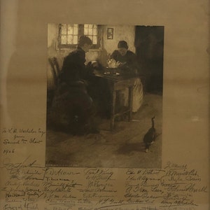 Puede incluir: Una fotografía en blanco y negro de dos mujeres sentadas a una mesa en una habitación con poca luz. Las mujeres visten ropa oscura y parecen estar mirando algo en la mesa. Un ganso camina en el fondo. La imagen está firmada por varias personas, incluyendo "Samuel T. Shaw" y "1906".