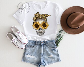 May include: White t-shirt with a graphic of a skull wearing a sunflower bandana and sunglasses. The skull has a black bandana with yellow sunflowers. The sunglasses are made of sunflowers.