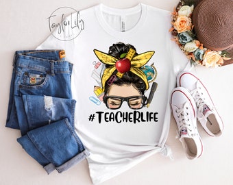 Könnte beinhalten: Weißes T-Shirt mit einem Aufdruck einer Frau mit einem unordentlichen Dutt, die eine Brille und ein gelbes Band mit einem roten Apfel trägt. Der Text "#TEACHERLIFE" ist unter dem Aufdruck gedruckt.