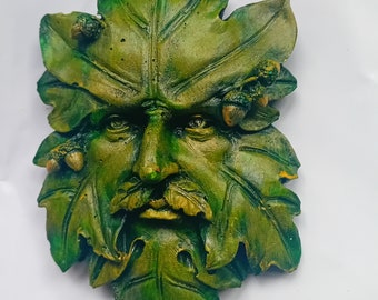 Könnte beinhalten: Wandbehang aus grünem Mann aus geformtem Harz mit einem Blattdesign und Eicheln. Das Gesicht ist mit einem Bart und einem Schnurrbart detailliert.