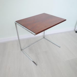 Peut inclure: Une table d'appoint en chrome et en bois avec un plateau rectangulaire et un design simple et moderne.