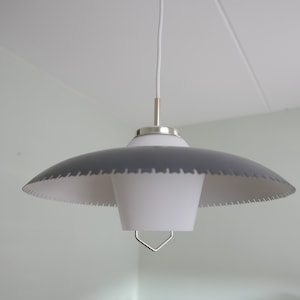 May include: A mid-century modern pendant light with a gray, scalloped shade and a white interior. The light fixture has a white cord and a silver-colored metal stem and a decorative metal piece at the bottom.