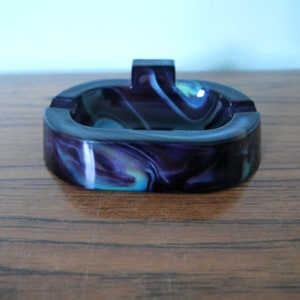 May include: A purple and blue swirl ashtray with a raised lip around the edge.
