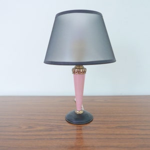 May include: A pink and black table lamp with a black lampshade. The lamp has a gold trim around the base.