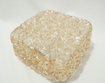 May include: A square, clear glass box with a textured, bubbly surface. The glass has a light amber color.