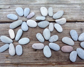 May include: A collection of smooth, gray and white stones arranged in a flower shape on a wooden surface.