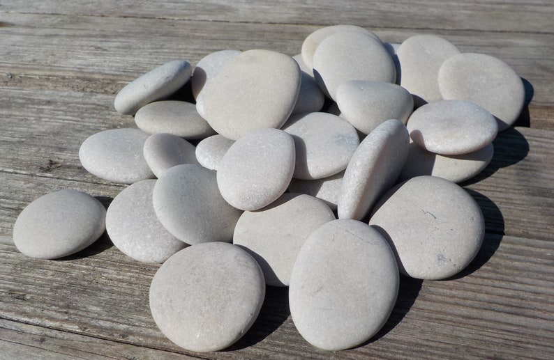 May include: A pile of smooth, white river rocks. The rocks are various sizes and shapes, and they are all very light in color.