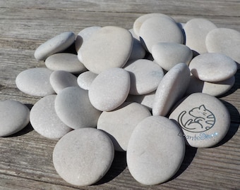 May include: A pile of smooth, white river stones. The stones are various sizes and shapes, and some have a slightly speckled appearance.