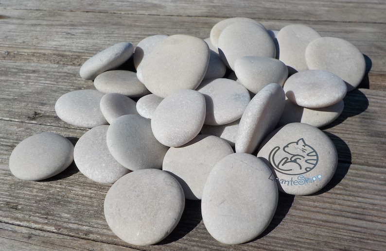 May include: A pile of smooth, white river rocks. The rocks are various sizes and shapes, and some have a slightly speckled appearance.