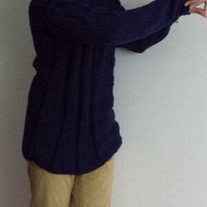 May include: A dark blue knitted sweater with long sleeves and a round neckline.